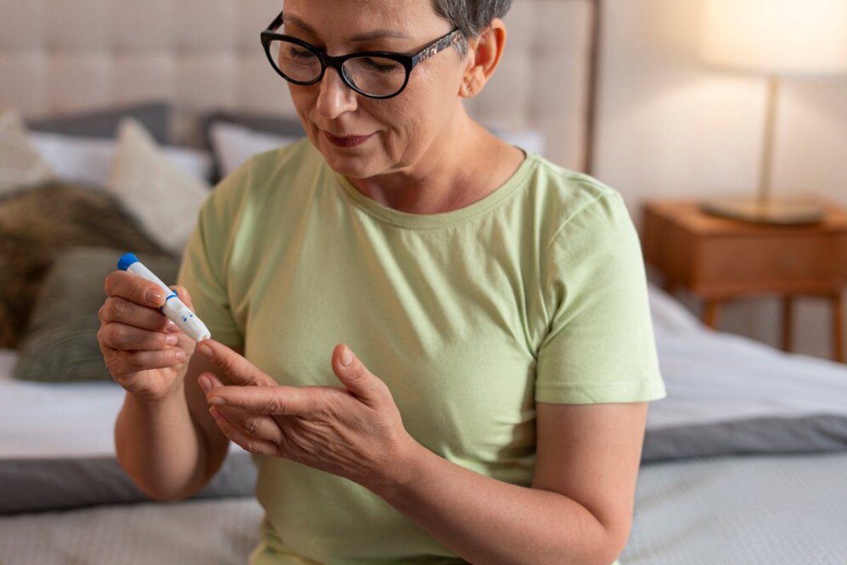A mature woman with glasses examining a diabetic lancet device in her bedroom.