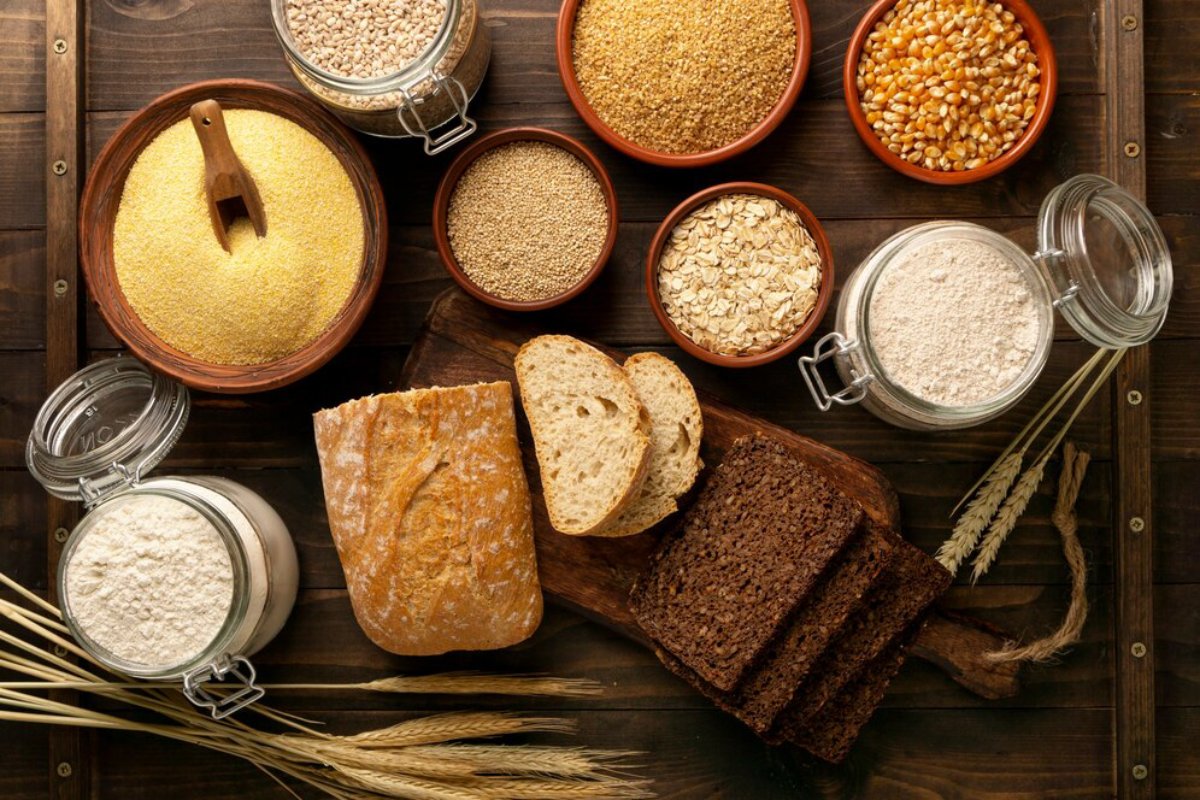 Assorted grains and sliced bread displayed on a wooden table, evoking a rustic farm-to-table feel.