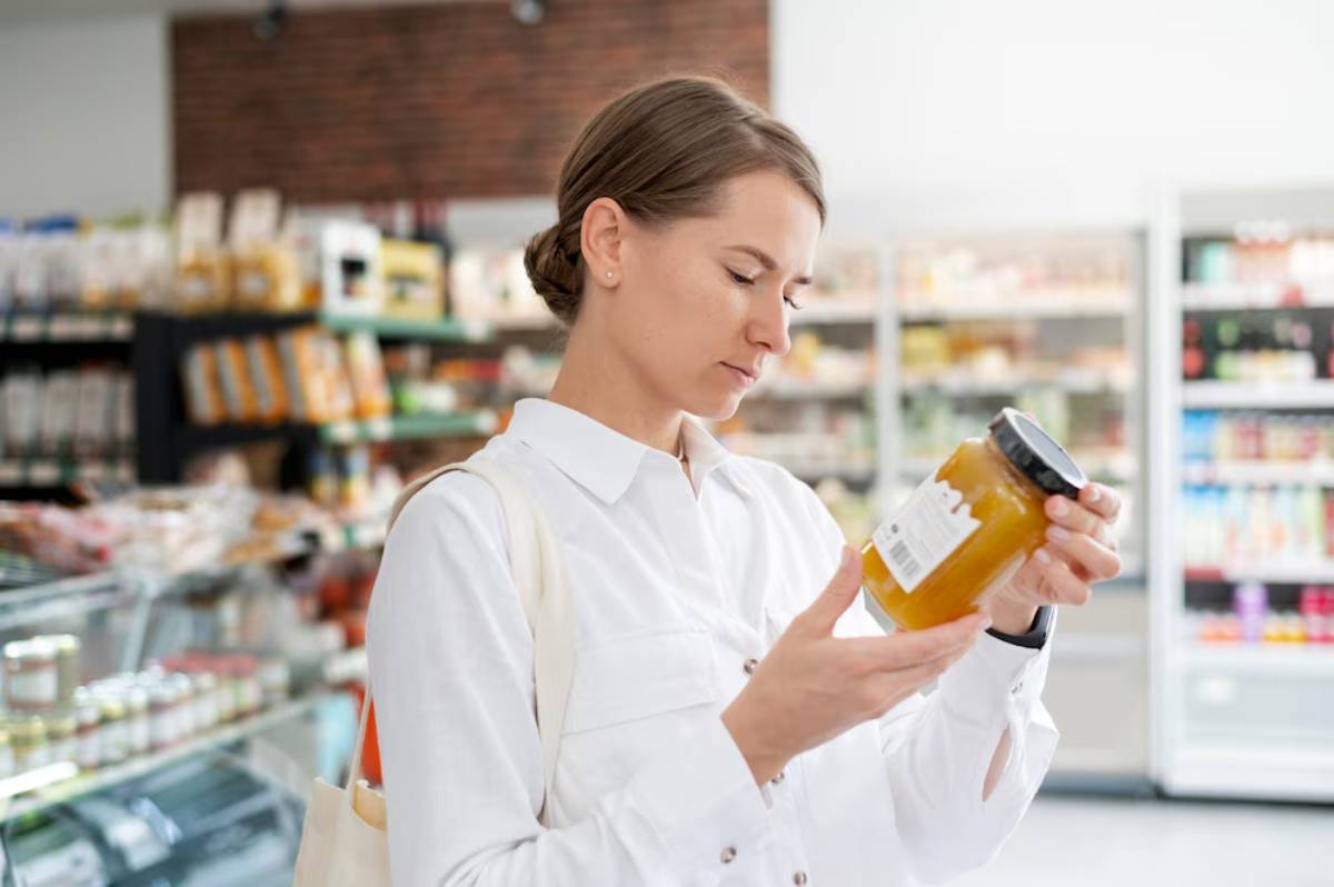Woman in a grocery store examining a jar of honey.