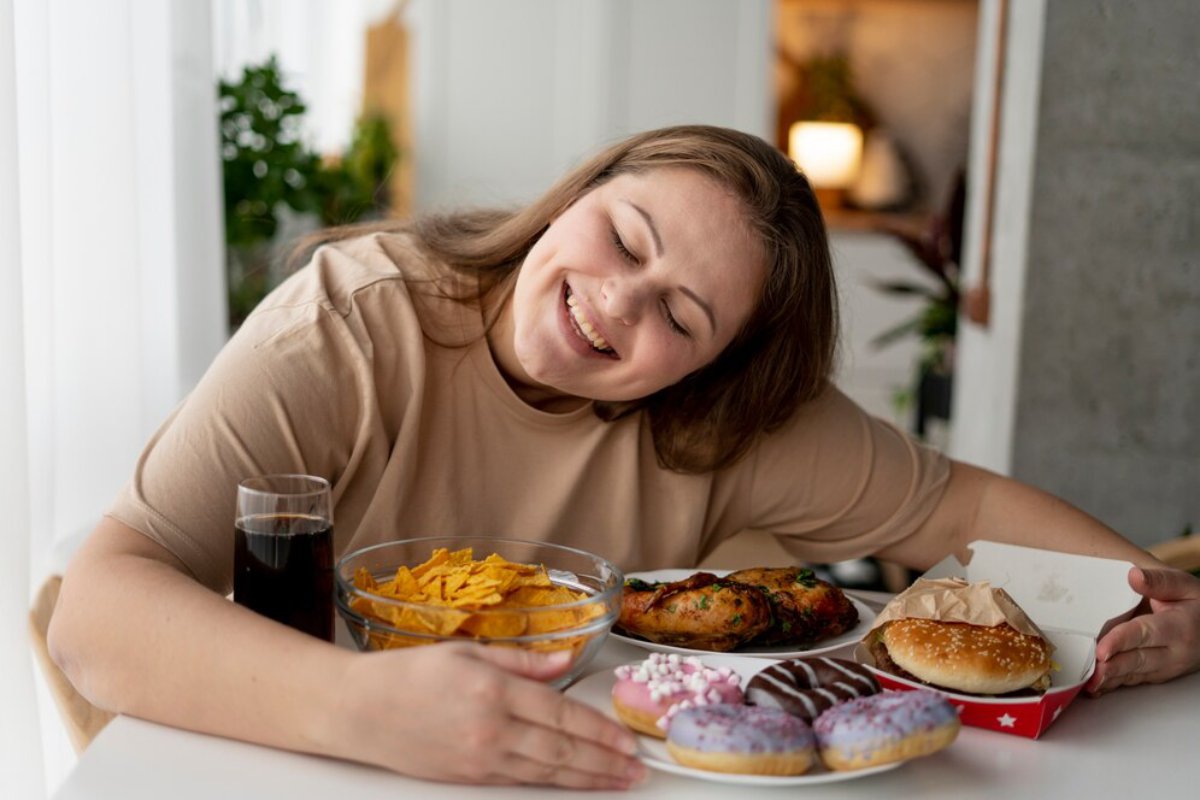Woman smiling while leaning on a table with a variety of fast food items.