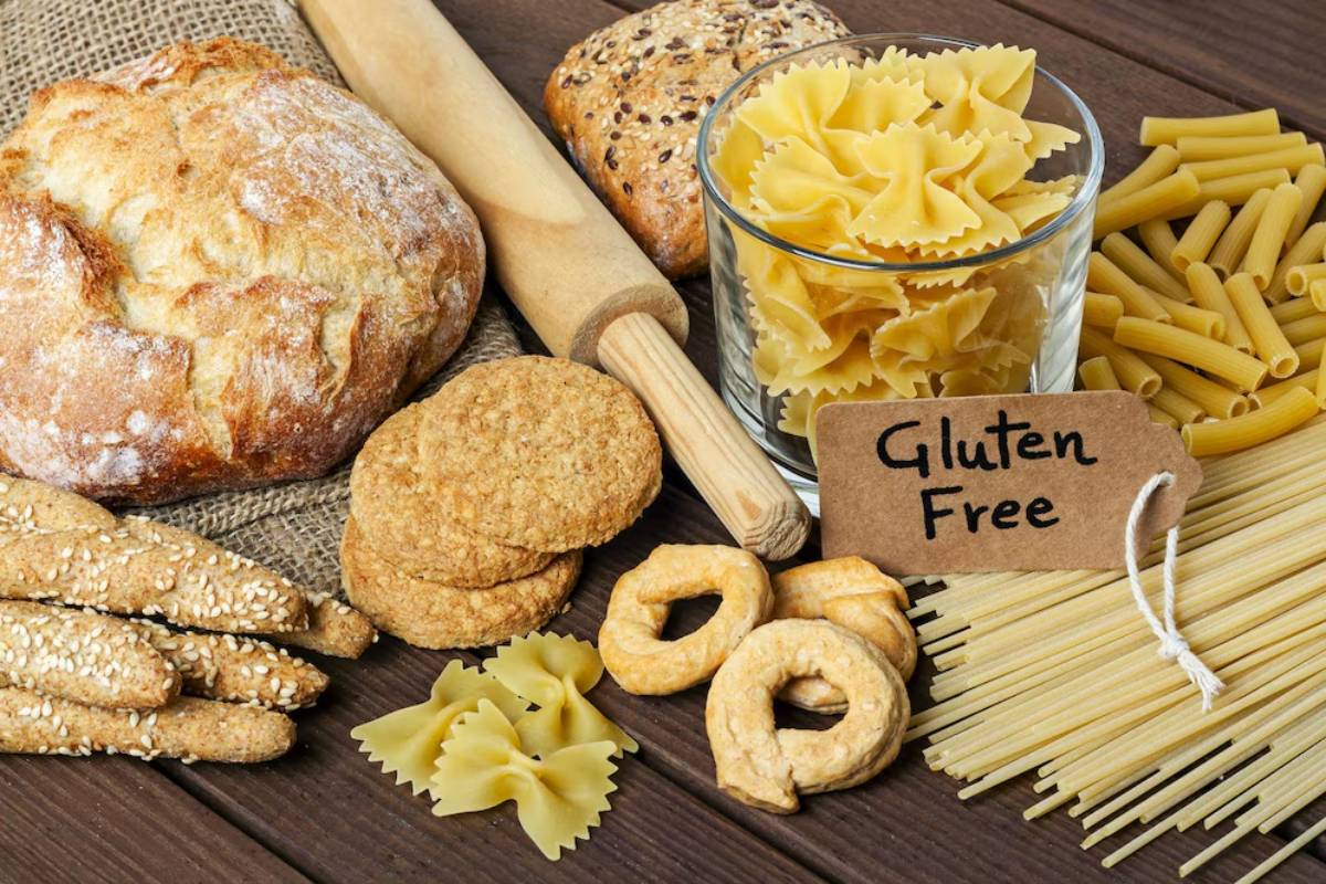 Assorted gluten-free breads, pastas, and cookies displayed on a wooden table with a 