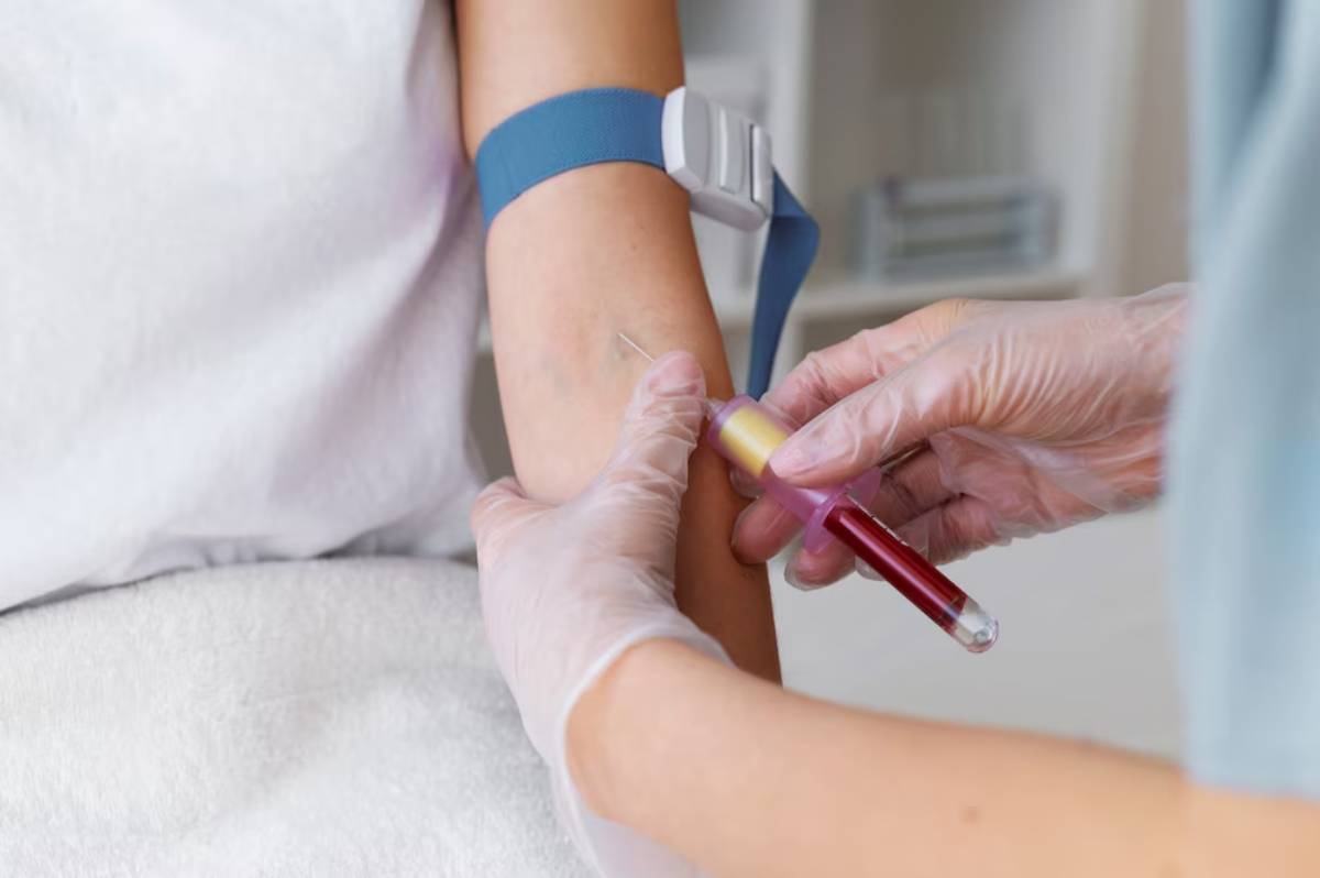 Healthcare professional drawing blood from patient’s arm while wearing gloves.