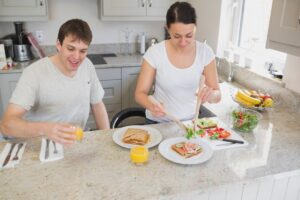 A young man and woman preparing breakfast together in a modern kitchen.