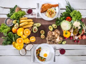 Assorted healthy meals and fresh fruits and vegetables spread on a rustic wooden table.