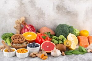 A variety of fresh fruits, vegetables, nuts, and fish displayed on a textured surface.